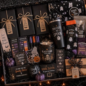 May include: A gift box containing three black-wrapped books with 'Just One More Chapter' tags, a 'Too Cute To Spook' tumbler, ghost-patterned socks, a 'Black Flame' candle, 'Haunted Caramel' popcorn, pens, bookmarks, and various spooky-themed stationery items.