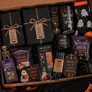 May include: A Halloween-themed gift box containing two black-wrapped gifts with tags reading Just One More Chapter, a mug saying Too Cute To Spook, ghost-patterned socks, a candle labeled Books & Boos, Witches Brew cocoa mix, and book accessories.