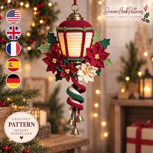 Könnte beinhalten: Ein gehäkeltes Weihnachts-Laternenornament mit einer rot-cremefarbenen Struktur, verziert mit roten und weißen Weihnachtssternen, grünen Blättern und einem spiralförmigen Schwanz mit drei kleinen goldfarbenen Metallglocken.