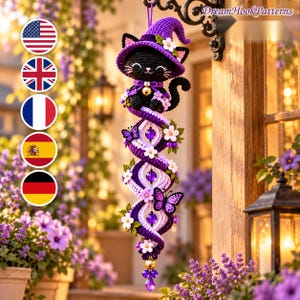 Puede incluir: Una decoración de ganchillo colgante que muestra un gato negro con un sombrero de bruja morado, suspendido sobre una estructura en espiral adornada con flores blancas, mariposas moradas y cuentas moradas, terminada con una pequeña campana dorada.