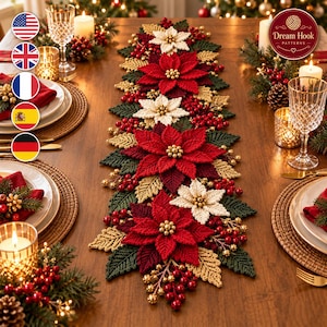 Puede incluir: Un camino de mesa navideño largo y decorativo con flores de pascua rojas y blancas tejidas a ganchillo, hojas de color verde oscuro y hojas doradas. El camino está acentuado con racimos de pequeñas bayas rojas y cuentas doradas.