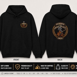 Op de afbeelding: Een zwarte hoodie met een kleine afbeelding op de linkerborst en een groot cirkelvormig ontwerp op de achterkant. De achterkant toont een kampvuur met rook, omringd door een gouden lauwerkrans en de tekst MEMBER I MADE SMOKE SOCIETY IMSS.