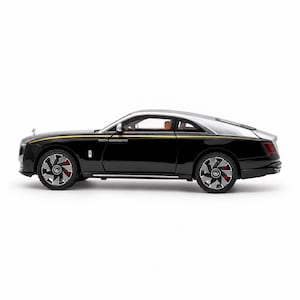 Könnte beinhalten: Ein schwarzes und silbernes zweitüriges Luxus-Coupé-Modellauto mit schlankem Profil, einem dünnen goldenen Zierstreifen entlang der Seite, Vielspeichenrädern mit roten Bremssätteln und einem durch die Seitenfenster sichtbaren orangefarbenen Innenraum.