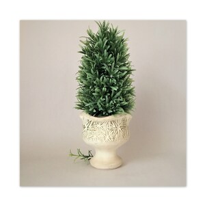 May include: A white ceramic planter with a decorative pattern, holding a green artificial topiary plant.