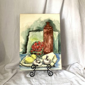 May include: Watercolor painting of a still life featuring a brown bottle, a box of red berries, lemons, and mushrooms on a blue tablecloth.