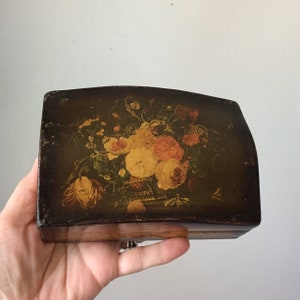 May include: A vintage wooden box with a hinged lid. The lid is decorated with a painted floral design featuring yellow, pink, and orange flowers on a dark brown background.