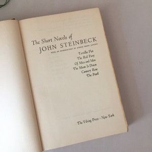 May include: A book cover with the title "The Short Novels of John Steinbeck" and a list of his novels: Tortilla Flat, The Red Pony, Of Mice and Men, The Moon Is Down, Cannery Row, and The Pearl. The book is published by The Viking Press, New York.