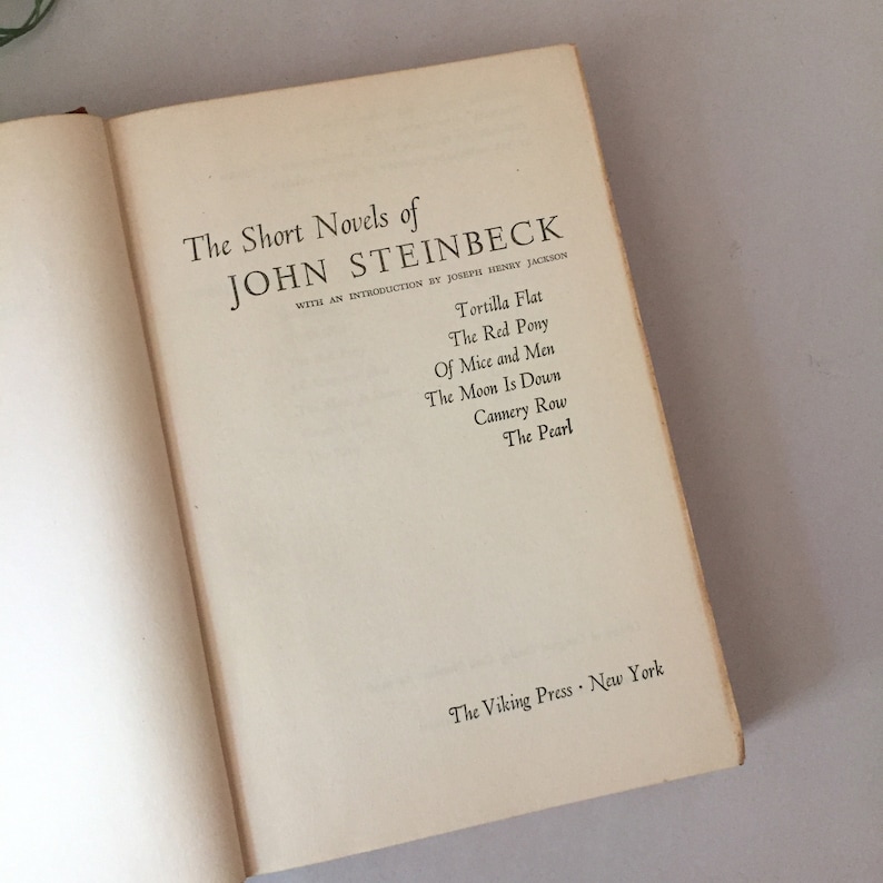May include: A book cover with the title "The Short Novels of John Steinbeck" and a list of his novels: Tortilla Flat, The Red Pony, Of Mice and Men, The Moon Is Down, Cannery Row, and The Pearl. The book is published by The Viking Press, New York.