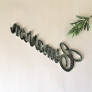 May include: A black metal sign with the word "dream" written in a decorative script font.