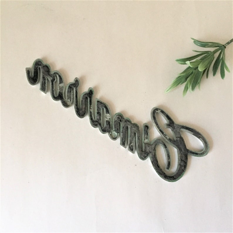 May include: A black metal sign with the word "dream" written in a decorative script font.