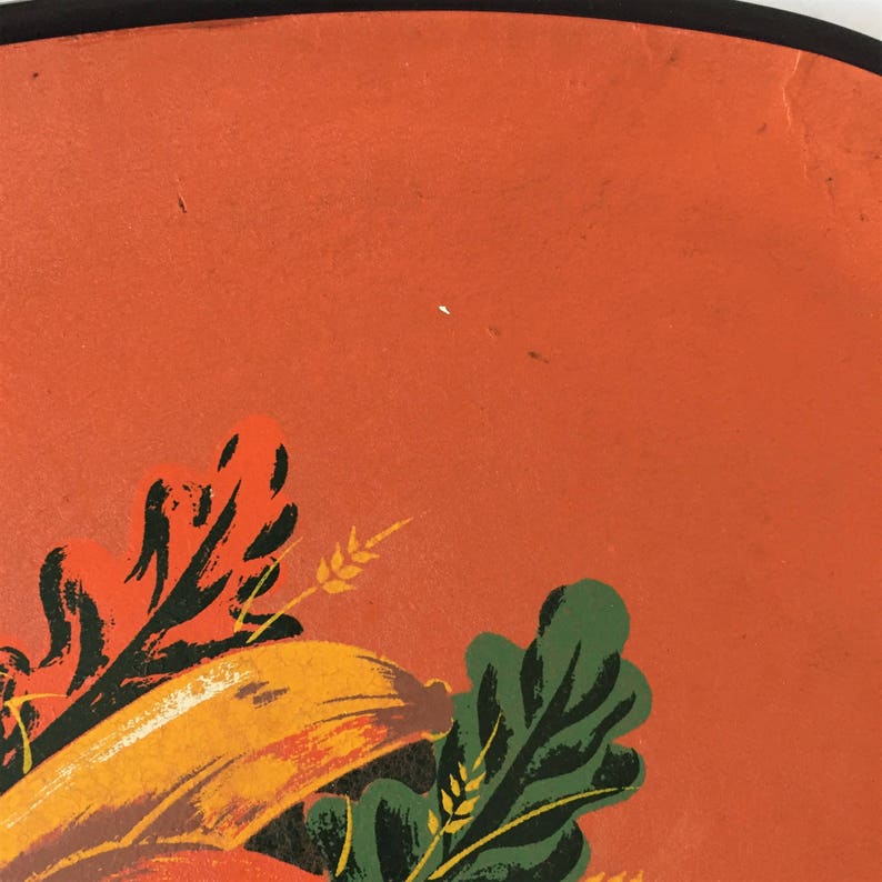 K&ouml;nnte beinhalten: Nahaufnahme eines orangefarbenen, bemalten Hintergrunds mit einem Design aus gr&uuml;nen und orangefarbenen Bl&auml;ttern und Weizen&auml;hren. Das Design befindet sich in der unteren rechten Ecke des Bildes.
