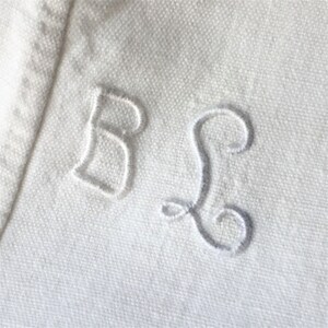 May include: White fabric with embroidered letters "B" and "S" in a cursive font.