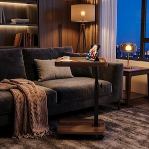 May include: A mobile side table with a dark wood grain finish, featuring a rectangular tabletop, a central adjustable metal support post with a black knob, and a square base on casters, holding a tablet and a white ceramic coffee cup.