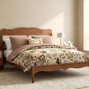 May include: A wooden bed frame with a curved headboard and footboard featuring woven cane paneling. The bed is dressed in a cream-colored duvet cover with a multi-colored botanical print of flowers, leaves, and butterflies, paired with solid mauve pillows.