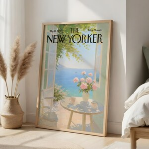 May include: A framed print of a May 12, 1979 The New Yorker magazine cover featuring an illustration of a balcony overlooking a blue sea. The scene includes a round table with a vase of pink flowers, two cups, and an open window with green foliage.