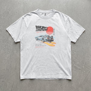 Könnte beinhalten: Ein hellgraues Kurzarm-T-Shirt mit einem Grafikdruck eines Sportwagens, der Feuerspuren hinterlässt. Das Design enthält den Text BACK TO THE FUTURE, eine rote Sonne und japanische Schriftzeichen. Das Shirt hat einen Rundhalsausschnitt.