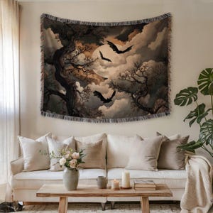 May include: A rectangular woven wall tapestry featuring a dark, atmospheric scene of a full moon partially obscured by clouds, silhouetted bare trees, and three flying bats. The tapestry has a decorative fringed edge on all four sides.