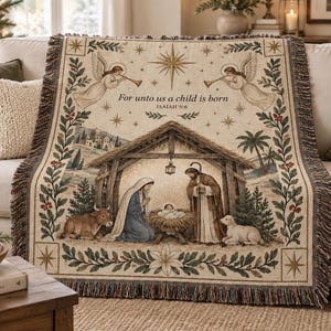 May include: A woven throw blanket featuring a nativity scene with Mary, Joseph, and the infant Jesus in a manger. The design includes angels, a star, and the text "For unto us a child is born ISAIAH 9:6" framed by a decorative floral border.