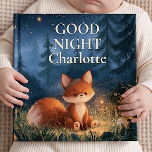 May include: A hardcover book titled Good Night Charlotte featuring a dark blue night forest scene with a small orange fox sitting in the grass. The cover displays a starry sky, tall pine trees, and glowing light particles around the fox.