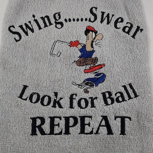 May include: Gray golf towel with embroidered text "Swing....Swear Look for Ball REPEAT" and a cartoon golfer.