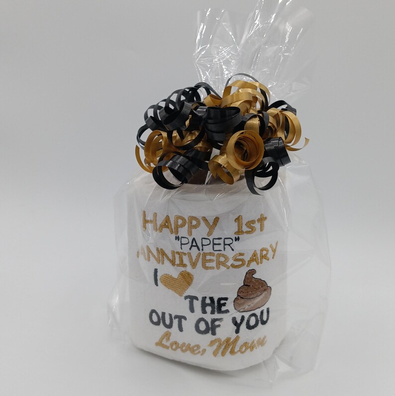 May include: A white ceramic mug with a black handle and the text "But First, Coffee" in a bold, black font. The mug is set against a blurred background, suggesting a cozy setting. The mug appears to be approximately 4 inches tall.