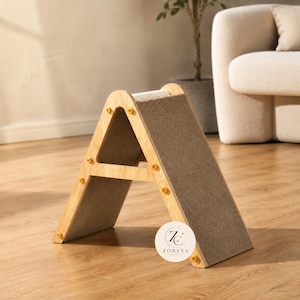 May include: A triangular pet scratching ramp made of light-colored wood with a textured gray carpet surface on the incline. The structure is held together by small yellow fasteners and features a circular logo with the text ZOREVA.