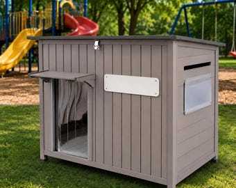 Puede incluir: Una caseta para mascotas de madera gris claro con techo inclinado, puerta frontal con solapa de plástico transparente, pestillo metálico en el borde superior, placa blanca rectangular en el panel frontal y una pequeña ventana lateral.