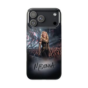 Puede incluir: Una funda transparente para smartphone con un estampado gráfico de Madonna actuando en el escenario con un corsé negro y mangas de rejilla. El diseño incluye una multitud de concierto de fondo y el nombre MADONNA escrito en negro abajo.