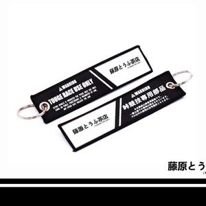 May include: Two rectangular black and white fabric keychains featuring the text WARNING TOUGE RACE USE ONLY and Japanese characters. Each keychain includes a silver metal split ring attached to one end for securing keys or other items.