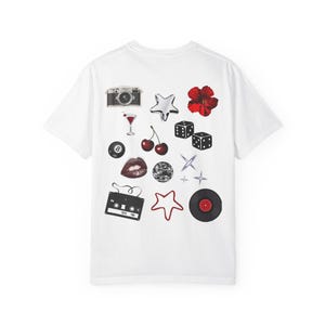 May include: A white t-shirt featuring a collection of various graphic icons printed on the back. The designs include a camera, a martini glass, a red flower, dice, cherries, an eight ball, lips, a disco ball, stars, a cassette tape, and a vinyl record.