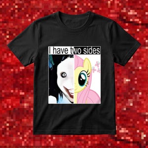 Può includere: Una t-shirt nera a maniche corte con una stampa grafica che riporta il testo I have two sides. Il design è diviso verticalmente, mostrando a sinistra un personaggio pallido dai capelli scuri con un ampio sorriso e a destra un pony giallo.