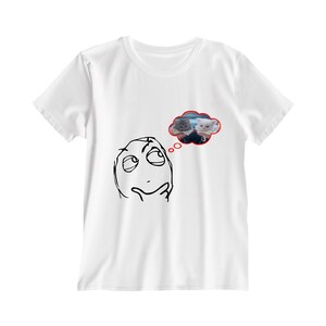 Puede incluir: Una camiseta blanca de manga corta con un dibujo de líneas negras de un rostro pensativo con una mano en la barbilla. Sobre el rostro hay una burbuja de pensamiento roja que contiene una fotografía de dos gatitos y el texto :3 en rojo.