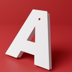 Puede incluir: Una letra A blanca en tres dimensiones con un acabado mate y liso. La letra presenta un pequeño orificio circular cerca del vértice superior, diseñado para colgar o montar. La estructura tiene bordes limpios y una forma sólida y gruesa.