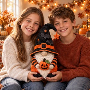 Peut inclure: Une poupée gnome crochetée avec un grand chapeau pointu noir à bordure orange, des appliques de chauves-souris grises et une petite étoile orange. Le gnome a une longue barbe blanche, des manches rayées noir et orange et tient une citrouille.