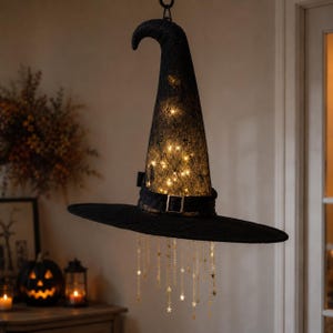 Può includere: Un cappello da strega in pizzo nero da appendere, dotato di luci LED interne bianco caldo, una fascia nera con fibbia color argento e numerose catenelle dorate con piccoli ciondoli a forma di stella che pendono dalla tesa.