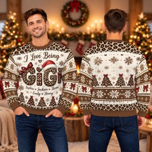 Peut inclure: Un sweat-shirt à col rond et manches longues avec une base crème et des motifs léopard marron. Le devant affiche le texte I Love Being GIGI avec un bonnet de Père Noël, des nœuds rouges et cinq prénoms. Le dos présente des flocons et sapins.