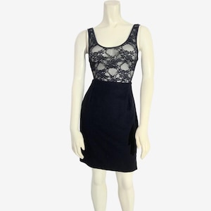 May include: A black dress with a lace bodice and a fitted skirt. The sleeveless dress is displayed on a mannequin against a white background. The lace bodice is a darker color than the skirt.