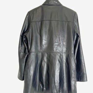 May include: Black leather jacket with a collared neckline and long sleeves. The jacket is hanging on a wooden hanger. The back of the jacket has a tailored design with vertical seams and a flared bottom.