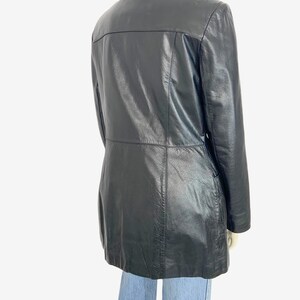 May include: A black leather jacket with a collared neckline and a tailored fit. The jacket has a button closure and a mid-thigh length. The back of the jacket features a horizontal seam across the upper back.