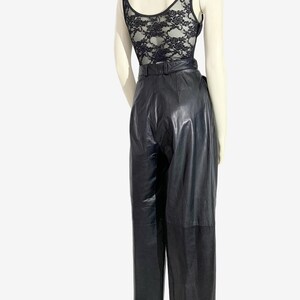 May include: A black lace bodysuit and high-waisted black leather trousers. The bodysuit has a scoop neck and a floral lace back. The trousers feature a belt and a straight-leg cut, creating a sleek, vintage-inspired outfit.