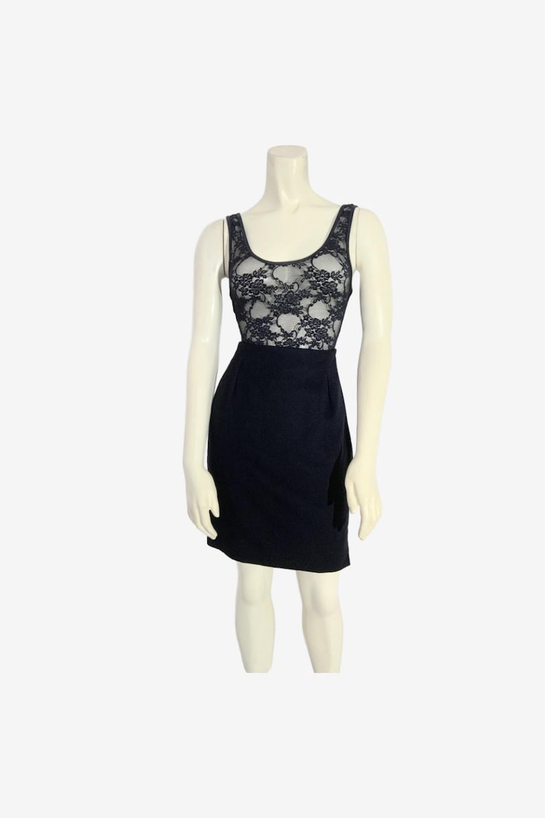 May include: A black dress with a lace bodice and a fitted skirt. The sleeveless dress is displayed on a mannequin against a white background. The lace bodice is a darker color than the skirt.