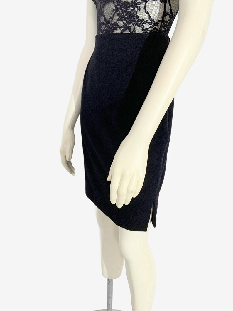 May include: A navy blue dress with a lace bodice and a fitted skirt. The dress is displayed on a mannequin. The skirt has a slit on the side.