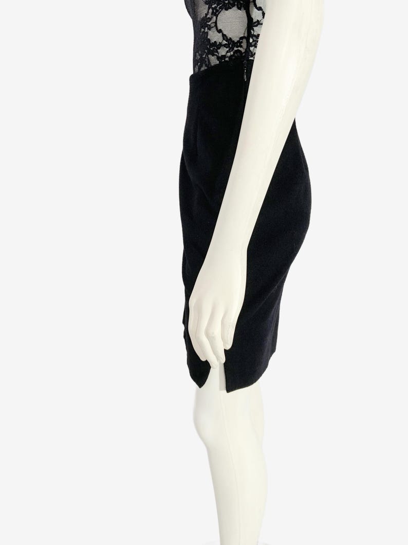 May include: A black pencil skirt with a side slit, paired with a black lace top. The skirt is knee-length and appears to be made of a soft fabric. The mannequin is white.