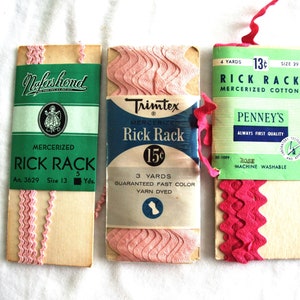 May include: Three vintage packages of pink and red mercerized rick rack ribbon. The packages feature green and blue labels with text including "Nalaskond", "Trimtex", and "Penney's". The ribbon is wavy and decorative.