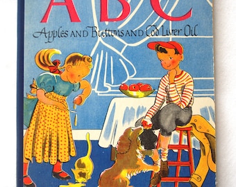 May include: Vintage children's book cover titled "ABC Apples and Buttons and Cod Liver Oil." The cover features illustrations of children, a dog, and a cat. The background is blue with white line drawings.
