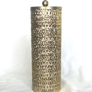 May include: A cylindrical gold-toned metal holder featuring an intricate, repeating openwork pattern throughout its body. The structure is topped with a small, centered spherical finial, creating a uniform, perforated design across the entire surface.