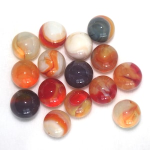 May include: A selection of colourful glass marbles in various sizes and patterns. The marbles feature swirls of orange, red, white, and blue, with some appearing translucent. The marbles are scattered on a white surface.