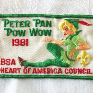 May include: Embroidered patch featuring Peter Pan in green and tan attire, with the text "Peter Pan Pow Wow 1981" in green and red. The patch also includes "BSA Heart of America Council" and a yellow fleur-de-lis.