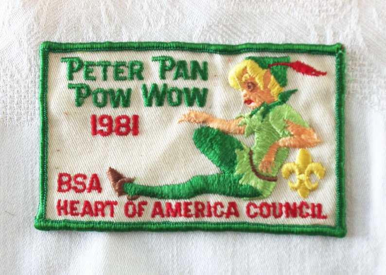 May include: Embroidered patch featuring Peter Pan in green and tan attire, with the text "Peter Pan Pow Wow 1981" in green and red. The patch also includes "BSA Heart of America Council" and a yellow fleur-de-lis.