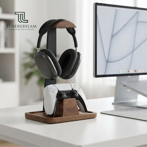 May include: A wooden headphone and controller stand featuring a dark walnut base and vertical support. The stand holds a pair of black over-ear headphones on the top arch and a white wireless gaming controller on the lower front mount.